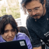 Una mujer y un hombre mirando la pantalla de un computador.