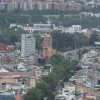 Vista panorámica de Bogotá con edificaciones residenciales y comerciales de diferentes alturas, avenidas arboladas y sectores urbanos que se extienden hacia el horizonte.