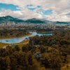 Vista aérea del parque Simón Bolívar en Bogotá, con zonas verdes, árboles, cuerpos de agua y los cerros orientales al fondo bajo un cielo parcialmente nublado.