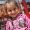 Foto de una niña sonriente con un saco rosado.
