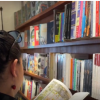 Imagen d eun holbre y una mujer leyendo un libro en una biblioteca.