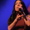 Imagen de una mujer joven que canta con un micrófono en su mano.