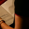 Imagen de una mujer de espalda, sentada leyendo un libro.