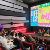 Imagen de varias personas en un escenario donde se ve una gran pantalla en la que se proyecta publicidad del BIFF 12.