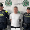 Foto de un hombre capturado en medio de dos policías.