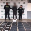 Foto de una persona capturado, dos policías y computadores recuperados