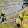 Bomberos rescatando a dos hombres que cayeron al canal de la avenida NQS.