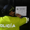 Foto que muestra una policía colocando un aviso de suspension en una reja negra
