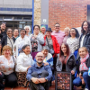 Foto de un grupo de personas de diferentes edades posando para una fotografía frente a un edificio.