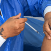 Foto que muestran unas manos colocando una vacuna en un brazo